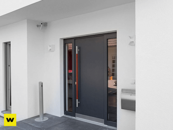 Moderne Haustür aus Aluminium mit Seitenteil in weißer Hausfassade und Briefkasten.